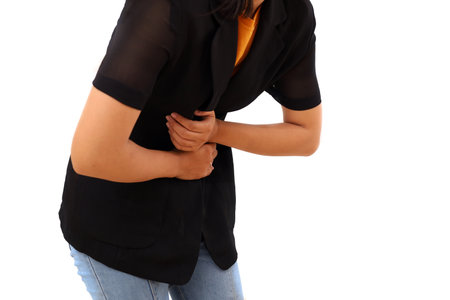 Close up photo of young woman suffering from stomach ache. Her hands holding her tummyの写真素材