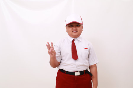 Elementary school student wearing red white uniform and showing three fingers. Isolated on whiteの写真素材