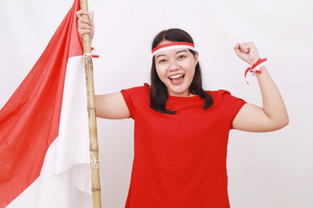 Young indonesian girl celebrate independence day while holding red white flag with clenched handの写真素材