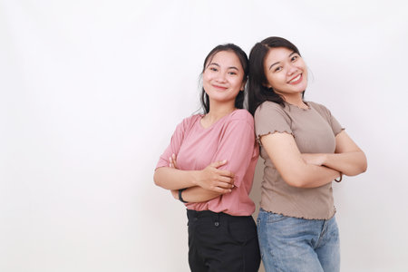 Portrait of two pretty asian young women standing against white background with copyspace