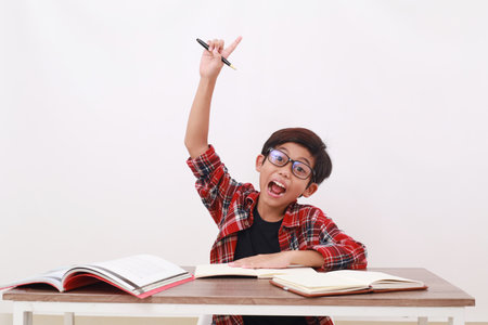 Excited asian student raising his hand while studying. Isolated on white backgroundの写真素材