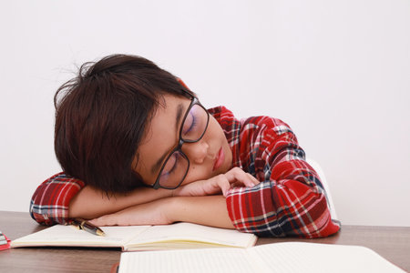 Close up photo of Tired asian student sleeping on the desk while studying. Isolated on white