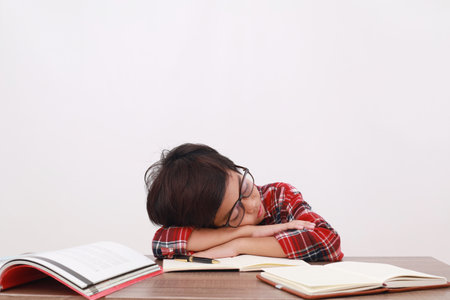 Tired asian student sleeping on the desk while studying. Isolated on white backgroundの写真素材