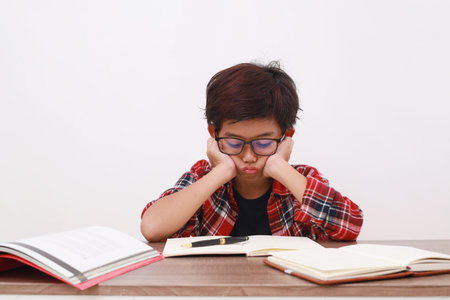 Stressed asian student studying with frown face expression. Isolated on white backgroundの写真素材