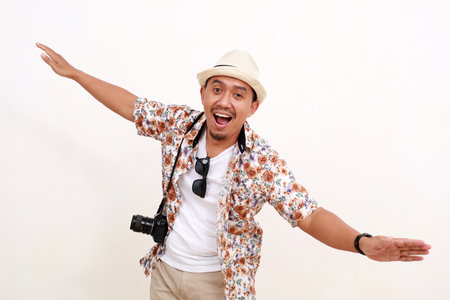 Happy asian adult man tourist standing while making flying gesture. Concept of travel. Isolated on white backgroundの写真素材