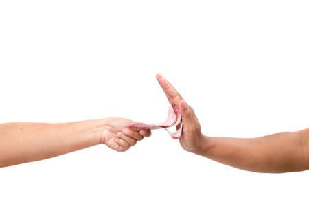 A human's hand gives a stack of money to a other hand, which refuses. Side view. White background. The concept of the world anti-corruption dayの写真素材