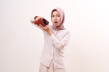 A person in a headscarf showing a surprised expression while looking at an empty wallet. Isolated on...