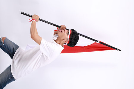 Asian men stand to celebrate Indonesia's independence by raising red and white flag sticks and...