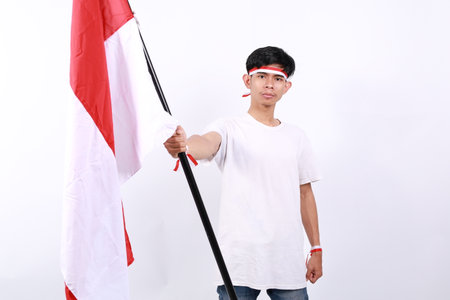 Asian men stand to celebrate Indonesia's independence by raising red and white flag sticks and...