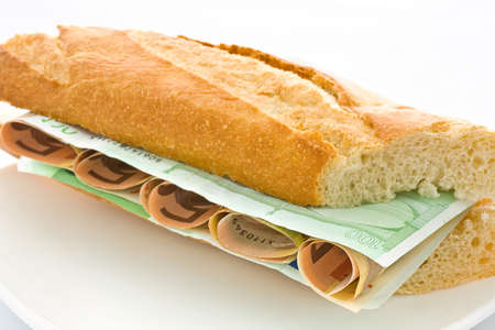 Fresh white loaf with a layer of monetary denominations insideの写真素材
