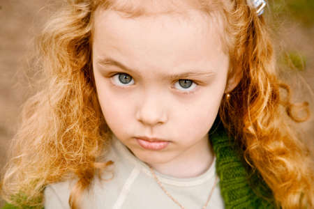 Portrait of the serious grey-eyed little girl with the long hair, looking in a shotの写真素材