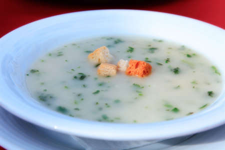 White plate with soup on a red clothの写真素材