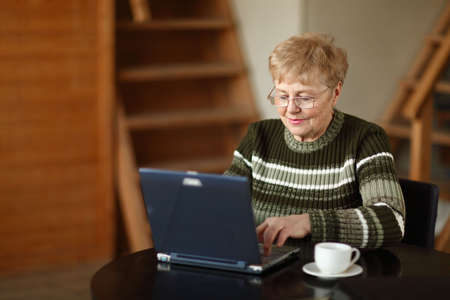The elderly woman writes  on the computerの写真素材