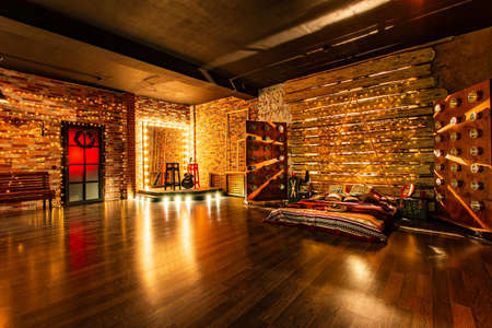 A guitar waiting for a player, large mirror with some lamps on the frame, a star like a bedhead