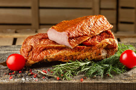 Smoked meat, Sliced smoked gammon on a wooden table with addition of fresh herbs and aromatic spices.の写真素材
