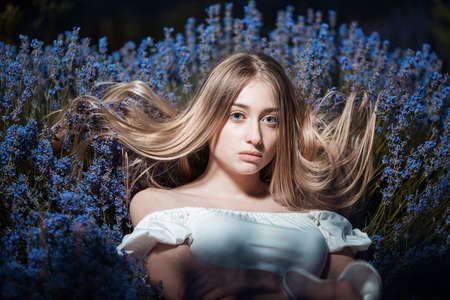 Beautiful blonde woman in the lavender field on sunset. Soft focusの写真素材