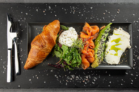 Italian panini sandwich, french croissant with salmon, avocado, rukkola and cream cheese on a rectangle plate.の写真素材