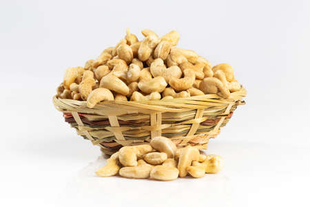 Cashew nuts in a wicker bowl. Isolated on white.の写真素材