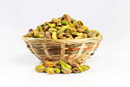 Green pistachios in wicker bowl. Dried and peeled raw kernels.の写真素材