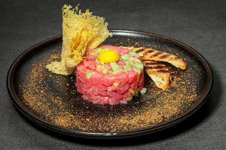Tuna tartare with cucumber, small leaves, egg yolk, chips and croutonsの写真素材