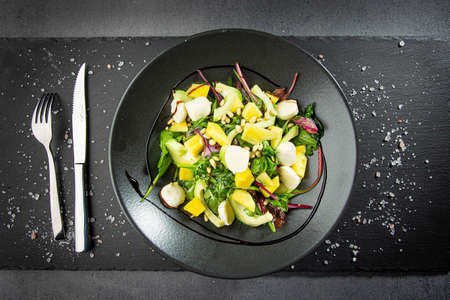 Fresh green salad with avocado, mango, mozarella on dark backgroundの写真素材