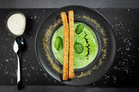 Top view of spinach cream-soup with bread sticks, dark surfaceの写真素材