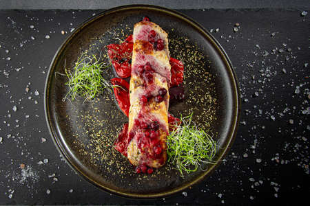 Baked pork meat glazed with cranberry sauce placed on grilled bell pepper, served with green sproutsの写真素材