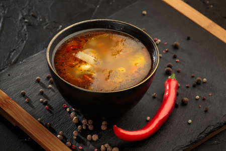 Chicken soup with vegetables in black bowl with red pepper and sour cream on black background.の写真素材