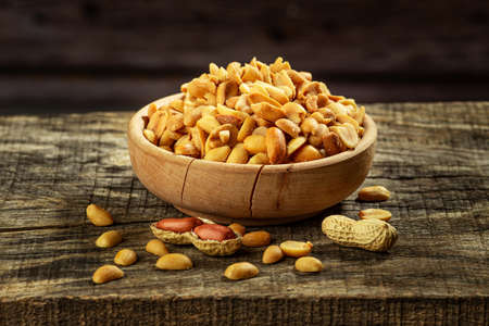 Dried salted peanuts in wooden bowl