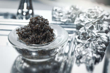 Black caviar. Black sturgeon caviar in a glass bowl on a silver trayの写真素材