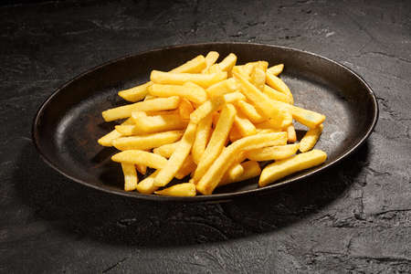 Potatoes fries in the plate isolated on dark