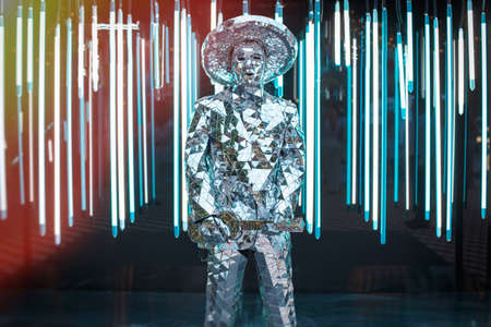 a male artist in a mirrored suit and hat with an electric guitar on a dark backgroundの写真素材