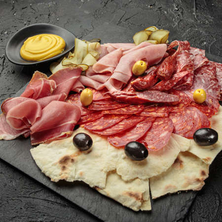 Charcuterie Board with Various Pickles and Meats - Cucumbers, Olives, Pepperoni, Ham and Flatbreadの写真素材