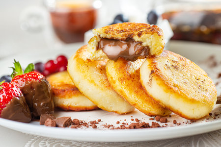 Cottage cheese pastries with strawberry, syrniki stuffed with chocolate on a white plate, selective focusの写真素材