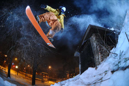 Jumping snowboarder in the city at night in winter Jumping snowboarder in the city at night in winter