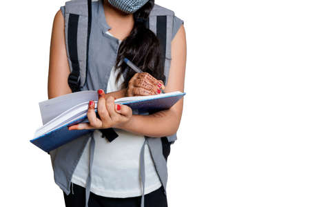The Indian lovely adorable charming little girl is looking down at the copybook in her hands and...