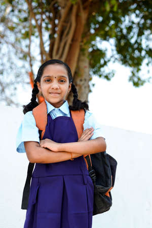 Smiling student girl wearing school backpack and holding exercise book. Portrait of happy asian young girl outside primary school. Closeup face of smiling schoolgirl looking at camera.の写真素材