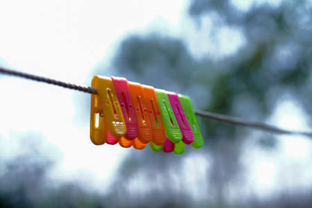Colorful clothespins hanging on clothesline against blurred background, closeupの写真素材
