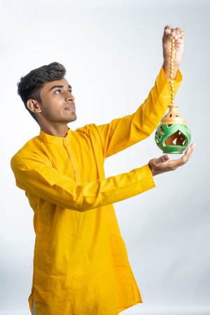 Young handsome indian man holding a lamp or hanging lamp