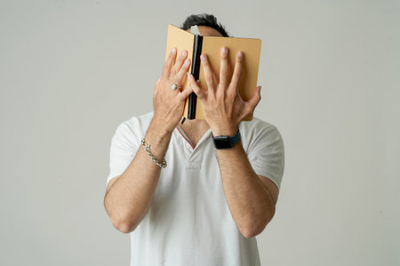 Young indian man standing with note book, isolated on whiteの写真素材