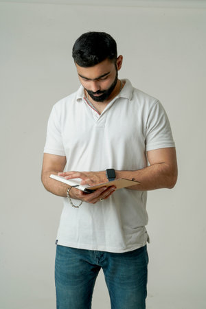 Young indian man standing with note book, isolated on whiteの写真素材