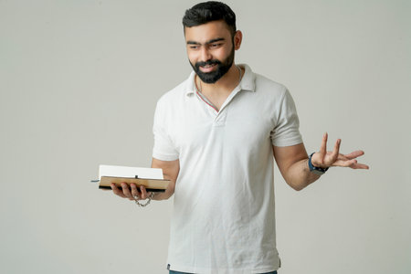 Young indian man standing with note book, isolated on whiteの写真素材