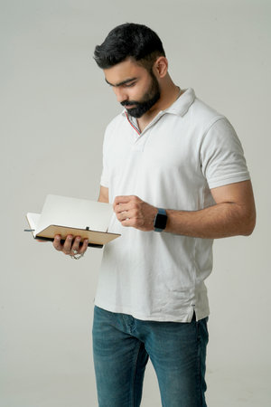 Young indian man standing with note book, isolated on whiteの写真素材