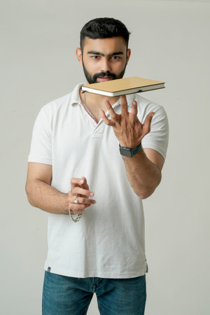 Young indian man standing with note book, isolated on whiteの写真素材