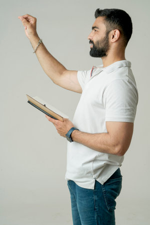Young indian man standing with note book, isolated on whiteの写真素材