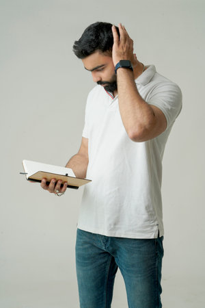 Young indian man standing with note book, isolated on whiteの写真素材