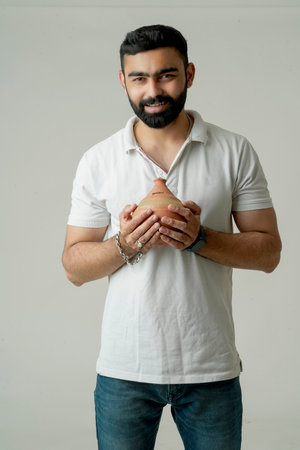 Portrait of Handsome young Indian man holding clay money box or clay piggy bankの写真素材
