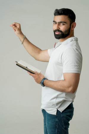 Young indian man standing with note book, isolated on whiteの写真素材