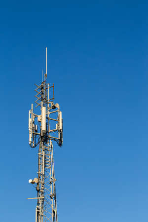 Telecommunication tower lit by the sun on a brigt blue background/sky text copy space to right