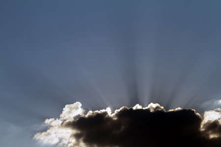 Sun rays at sunset in the clouds on blue sky background